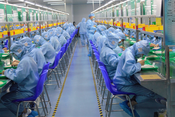 Workers in blue scrubs sitting in rows at desks working
